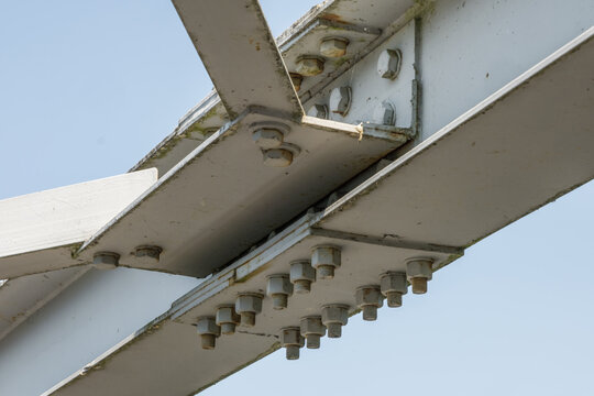 Bolts and nuts on metal plates of steel structure of heavy duty straight crossbar of frame and bridge support
