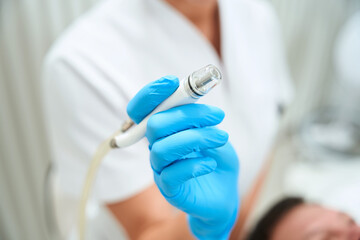 Esthetician holds the laser module of a modern device in his hands