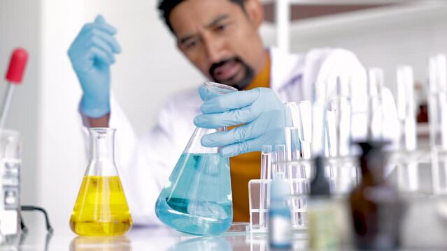 Professional scientist with beard drop liquid blue and yellow solution, teacher analyzed experimental results in science room, medical science test tube with chemical fluid testin in laboratory lab.