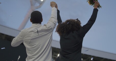 Black Male and Female Athletes Celebrate a Win on a podium after receiving gold medal