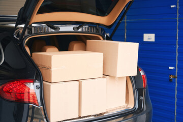 Cropped photo of car with cardboard boxes in the trunk into warehouse