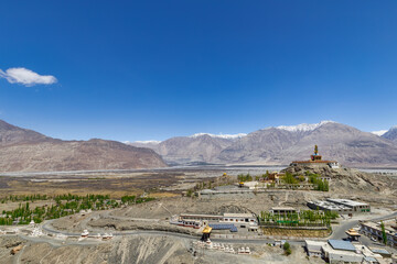 Big Sitting Buddha Statue at Diskit Monastery with Himalaya Range in the back - Nubra Valley, Ladakh, India
