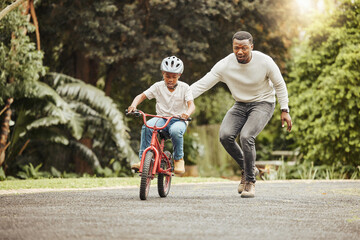 Family, father teaching child cycling in park with bicycle and helmet for safety, learning and...