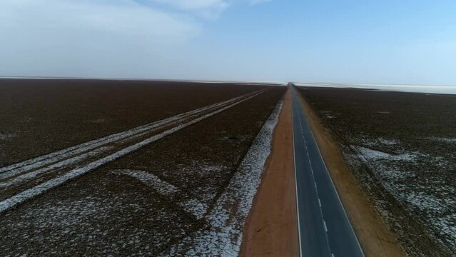 A road in a scary vast swamp plain in the special desert. Flying by drone.