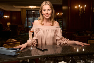 Woman with wonderful smile spending time at the desk counter in bar