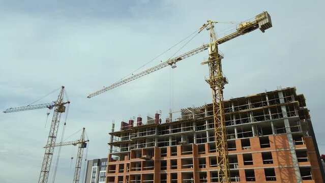Tower cranes and frame structure of high residential apartment buildings at construction site. Real estate development