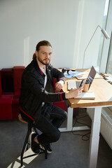 Diligent man facing camera while working at his workplace