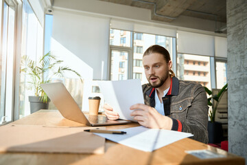 Male employee surprised while reading notes indoors