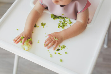 children's hands on a table with pieces of broccoli