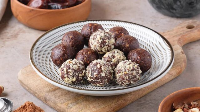 Zoom in homemade raw chocolate energy balls of dates, cocoa, coconut sprinkles and chopped 
hazelnut. Healthy vegan and vegetarian food. Sugar free nutrition. 4K video.