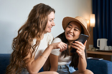 Happy female friends choose on Internet place to travel