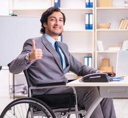 Young handsome employee in wheelchair at the office