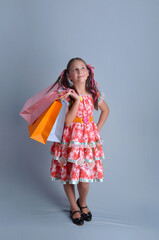 Menina com vestido de festa junina  sorridente com sacolas de compras 