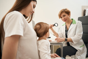 Qualified pediatric eye doctor checking child vision during primary consultation