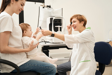 Pediatric ophthalmologist examining little patient during initial consultation