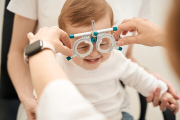 Eye specialist preparing little patient for visual acuity test - obrazy, fototapety, plakaty