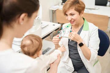 Fototapeta premium Pediatric ophthalmologist showing ophthalmic device to child