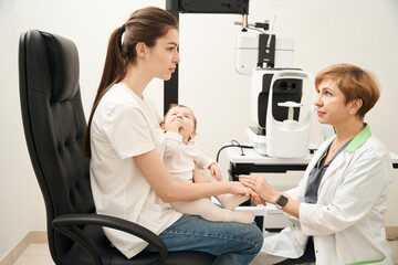 Pediatric ophthalmologist consoling parent after infant eye exam