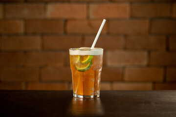 Glass of lime caipirinha drink on a table in front of a brick wall with space for text