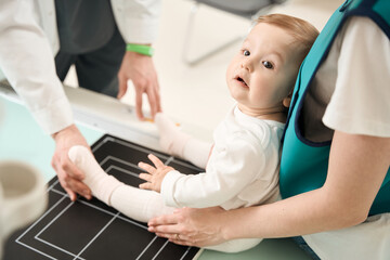 Experienced radiographer getting infant ready for lower limb x-ray