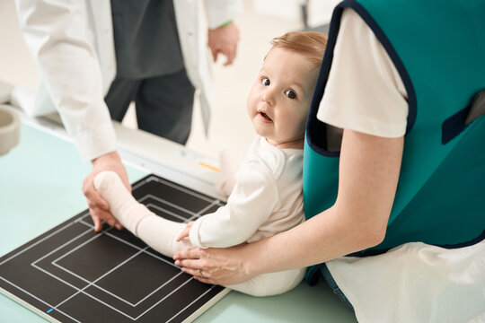 X-ray technician preparing small child for lower limb radiography