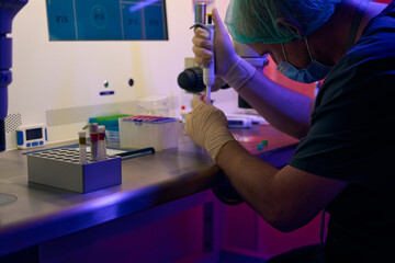 Biolaboratory worker adding fluid sample with micropipette