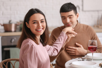Young man kissing his girlfriend's hand on a date in kitchen