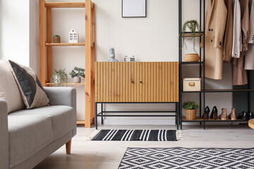 Interior of stylish living room with wooden cabinet, shelving unit and armchair