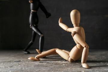 Wooden mannequins on table against dark background. Domestic violence concept - obrazy, fototapety, plakaty