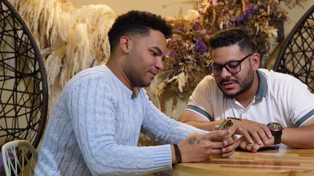 Dos amigos conversando sobre un viajes y mostrando registros en el celular - migos que Reviven sus Aventuras y Comparten sus Mejores Momentos de Viaje - Dos amigos mirando un celular