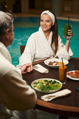 Couple having lunch by indoor swimming pool