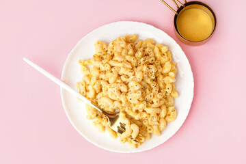 Plate of tasty Italian pasta with Cheddar cheese on pink background