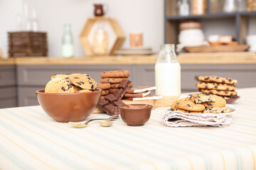 Cookies with chocolate and bottle of milk on table in kitchen