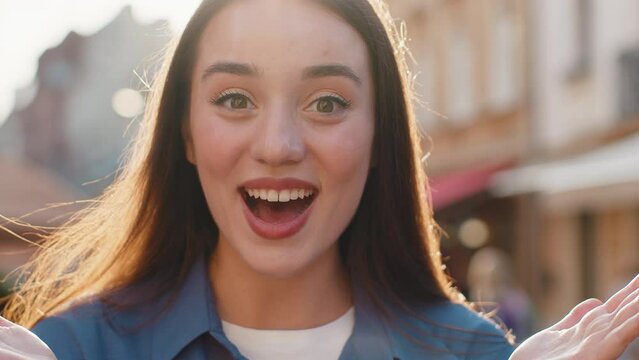Oh my God, Wow. Young pretty woman looking surprised at camera with big open eyes, shocked by sudden victory, game winning, lottery goal achievement, good news outdoors. Lovely girl in city street