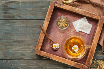 Cup of hot chamomile tea on dark wooden background