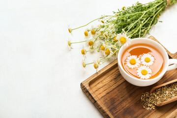 Cup of hot chamomile tea on light background