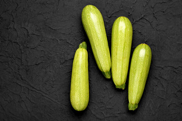 Many fresh green zucchini on black background