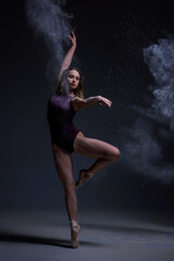 Fototapeta na wymiar Ballerina Jumping, Modern Ballet Dancer in Pointe Shoes, Black Background, Woman is dancing, a cloud of flour is around her. On hair at the woman white flour, it scatters dust about the room.