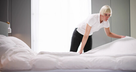 Young Female Housekeeper Changing Bedding