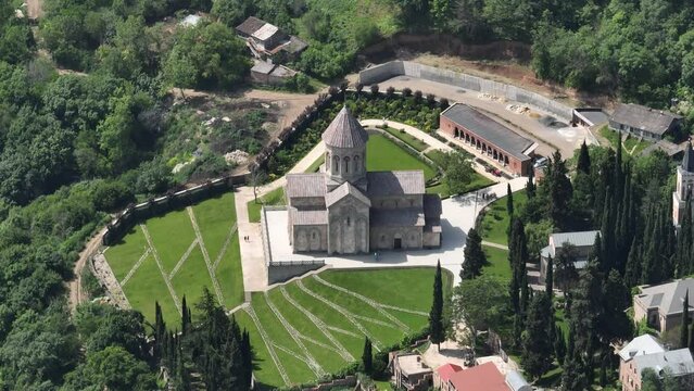 Aerial view of monastic complex of Bodbe nunnery on hillside among tall Cypress trees with Church of St. Nino on sunny day, Sighnaghi, Georgia