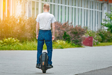 Man ride on monowheel down the city street. Man driving electric mono wheel (EUC), ecological transport in city. © Tricky Shark