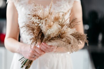 White wedding dress with lace on the bride holding a bouquet in boho style.