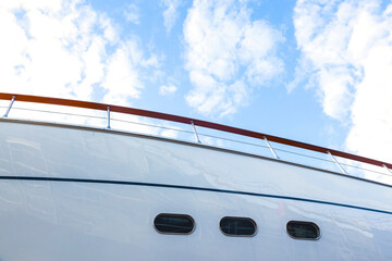 Hull of a luxury motorized white yacht with portholes, bottom view.