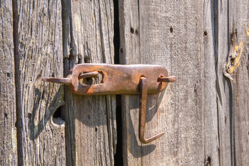 An old, original doorknob on a centuries-old wooden barn door in the harsh afternoon sun. Day. - 609412283