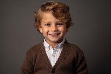 Portrait of a smiling little boy with curly hair on a dark background