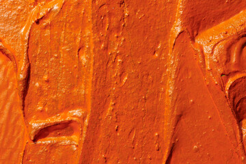 Decorative orange putty background. Wall texture with filler paste applied with spatula, chaotic...