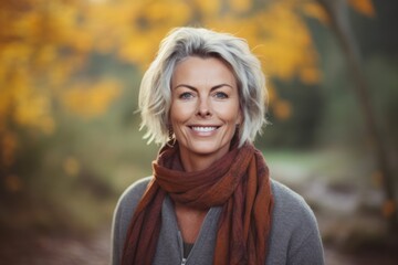 Portrait of a beautiful middle aged woman standing in an autumn park