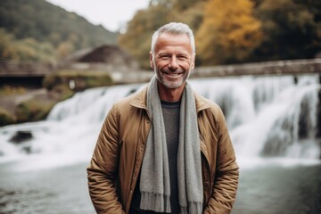 Portrait of a smiling senior man standing in front of a waterfall
