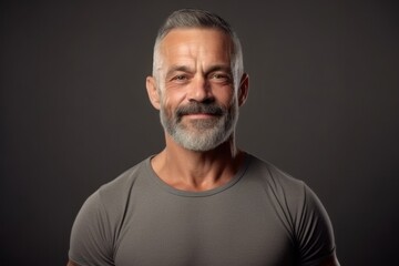 Portrait of handsome mature man in grey t-shirt on dark background