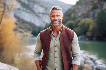 Medium shot portrait photography of a grinning man in his 40s that is wearing a chic cardigan against a mountain valley or canyon background . Generative AI